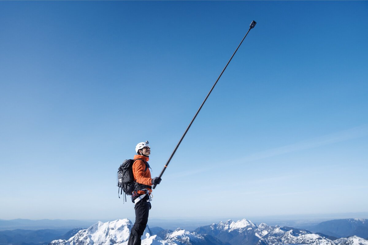 Person holding a fully extended DJI Osmo 2.5m carbon fiber selfie stick on a mountain